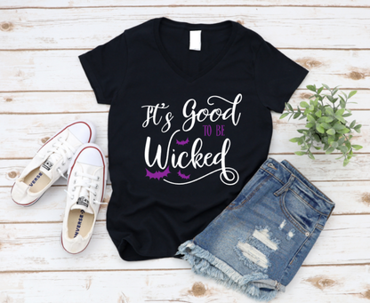 Black t-shirt with 'It's Good to be Wicked' text, paired with white sneakers and denim shorts on a wooden surface. www.missmafia.com