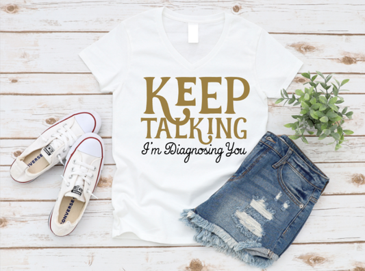 White t-shirt with 'KEEP TALKING I'm Diagnosing You' text, white sneakers, and denim shorts on a wooden surface. www.missmafia.com