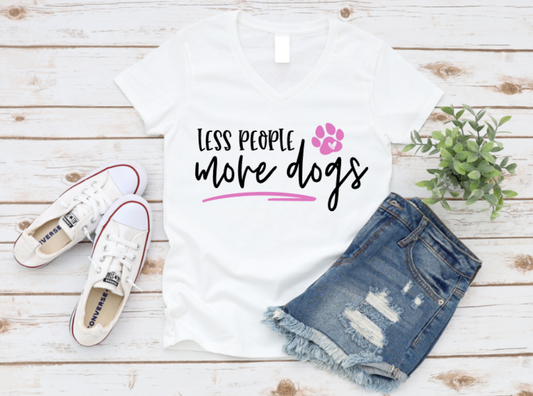 White t-shirt with 'Less people, more dogs' text, white sneakers, and denim shorts on a wooden surface. www.missmafia.com