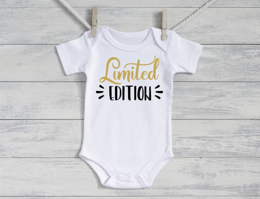 White baby onesie with 'Limited Edition' text on a wooden surface