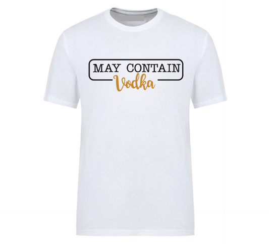 Flat lay of a white t-shirt with the phrase “May Contain Vodka” in black and gold text, styled with denim shorts and white Converse sneakers on a wooden background.