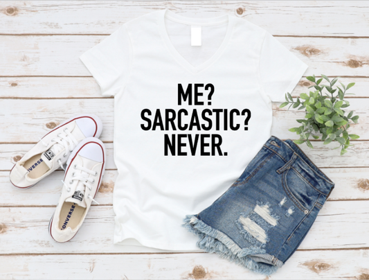 White t-shirt with 'ME? SARCASTIC? NEVER.' text, white sneakers, and denim shorts on a wooden surface. www.missmafia.com