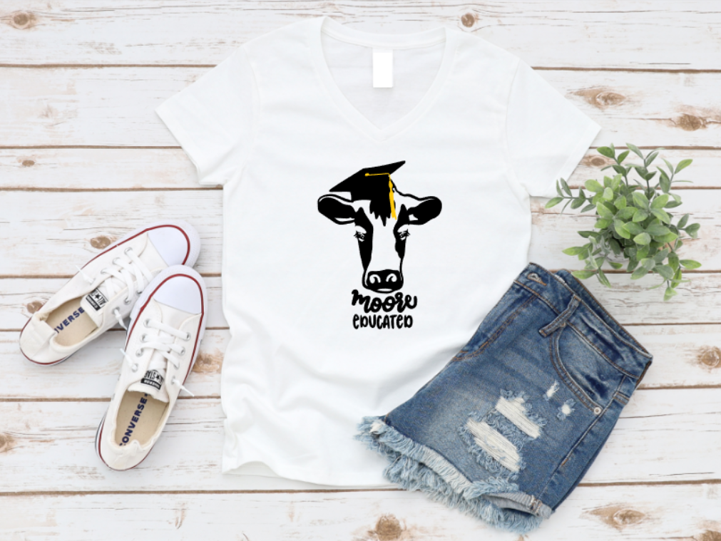White t-shirt with a cow graphic and text, paired with denim shorts and white sneakers on a wooden surface. www.missmafia.com
