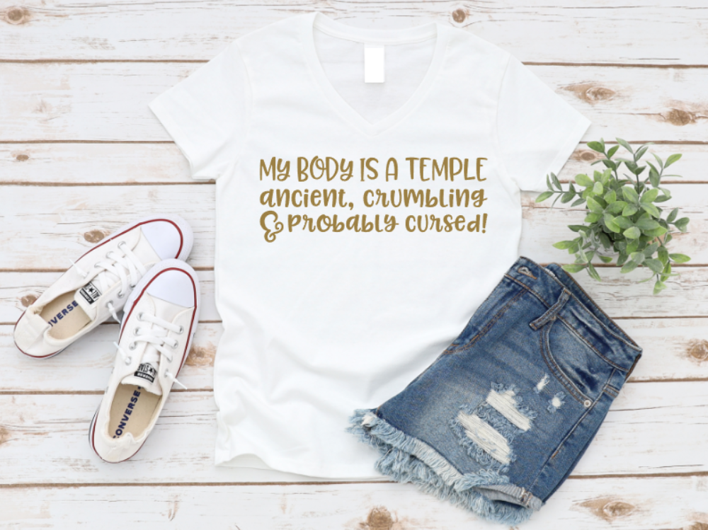 White t-shirt with humorous text, white sneakers, and denim shorts on a wooden surface. www.missmafia.com