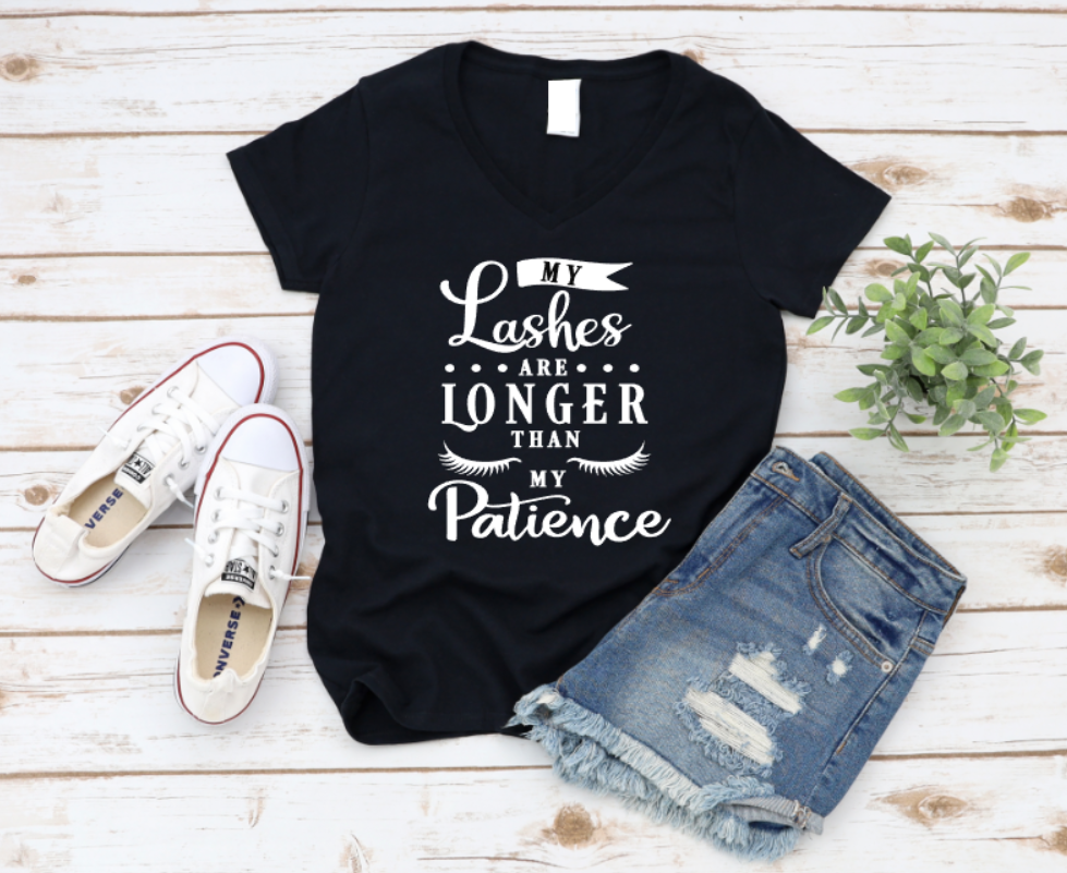 Black t-shirt with 'My Lashes Are Longer Than My Patience' text, paired with white sneakers and denim shorts on a wooden surface. www.missmafia.com