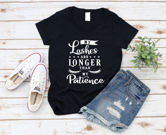 Black t-shirt with 'My Lashes Are Longer Than My Patience' text, paired with white sneakers and denim shorts on a wooden surface. www.missmafia.com