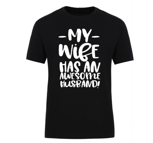 Black t-shirt with bold black text that reads “My Wife Has an Awesome Husband,” displayed flat with casual jeans and white sneakers – a humorous gift idea for confident husbands.