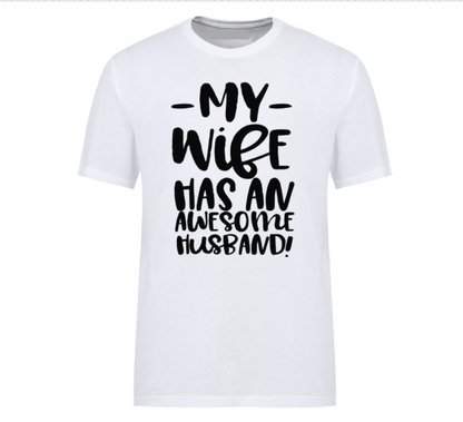 White t-shirt with bold black text that reads “My Wife Has an Awesome Husband,” displayed flat with casual jeans and white sneakers – a humorous gift idea for confident husbands.