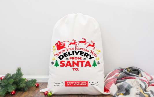 White sack with Christmas-themed text and graphics on a wooden floor with decorative items.