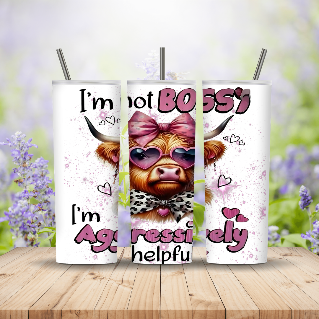 Three tumblers with cow designs and text on a wooden surface with a blurred floral background