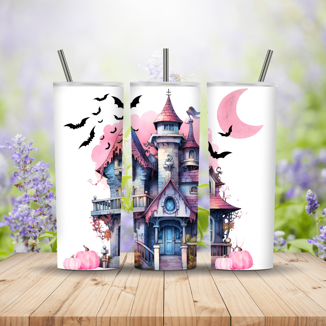Three tumblers with Halloween-themed designs featuring a haunted house, pumpkins, and bats on a wooden surface with a blurred floral background.