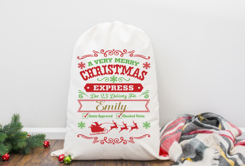 Personalized Christmas sack with festive design and text on a wooden floor.