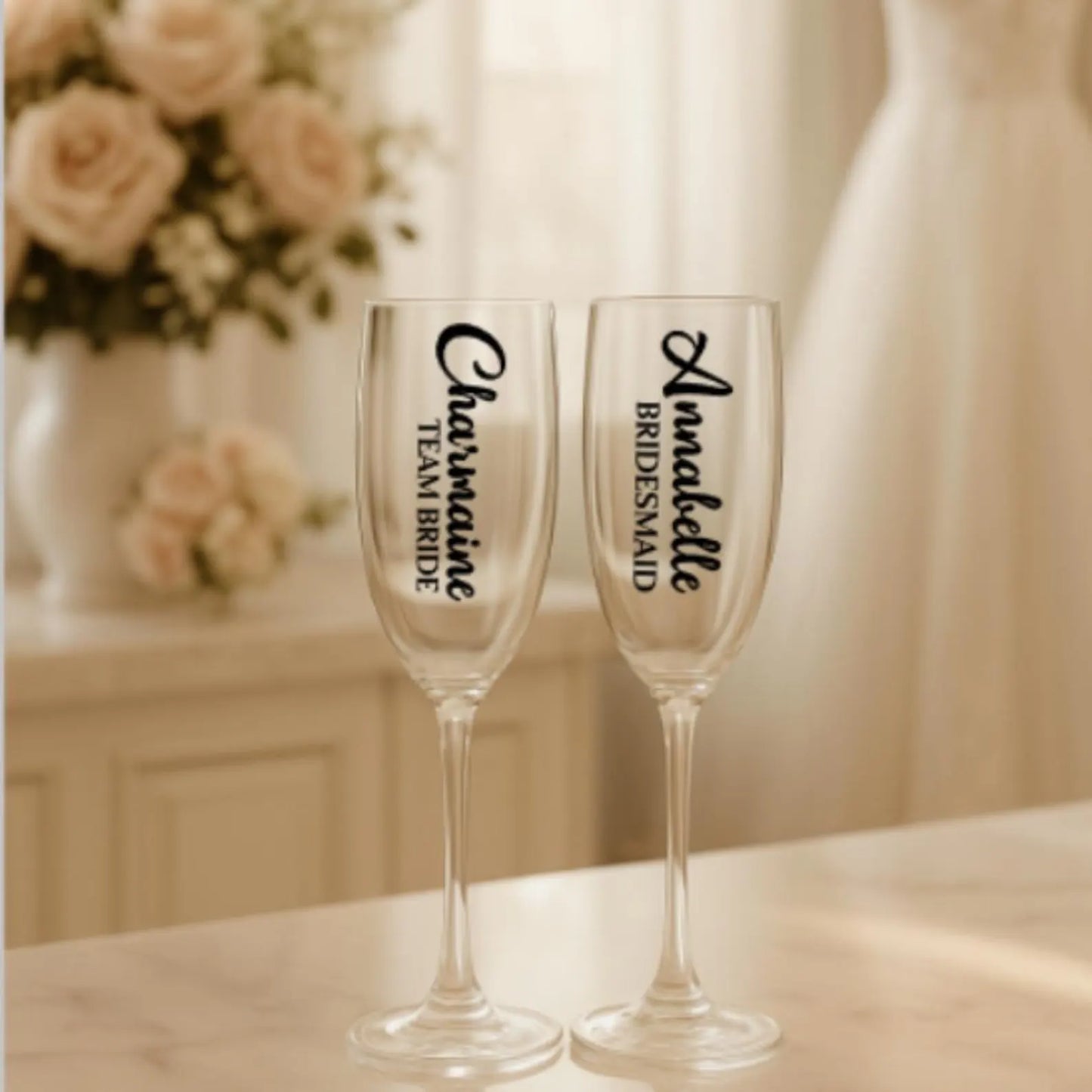 Two champagne flutes with personalized names on a blurred floral and indoor setting background