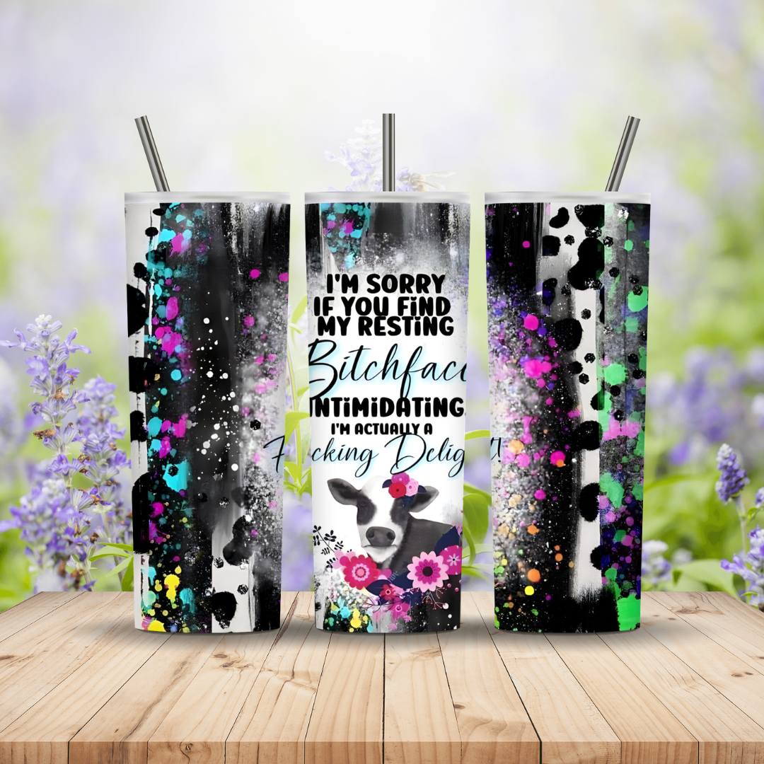 Three tumblers with artistic designs and text on a wooden surface with a floral background.