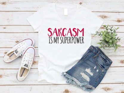 White t-shirt with 'Sarcasm is my superpower' text, paired with denim shorts and white sneakers on a wooden surface. www.missmafia.com