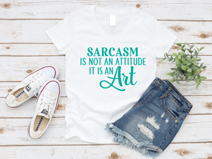 White t-shirt with 'Sarcasm is not an attitude, it is an art' text, paired with denim shorts and white sneakers on a wooden surface. www.missmafia.com