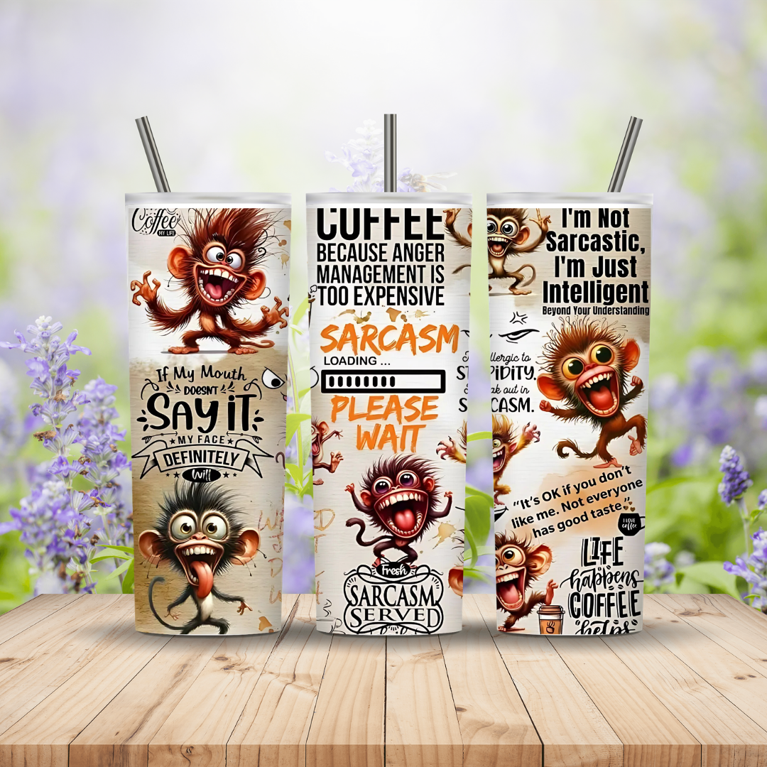 Three tumbler with cartoon monkey design and humorous text on a wooden surface with blurred floral background
