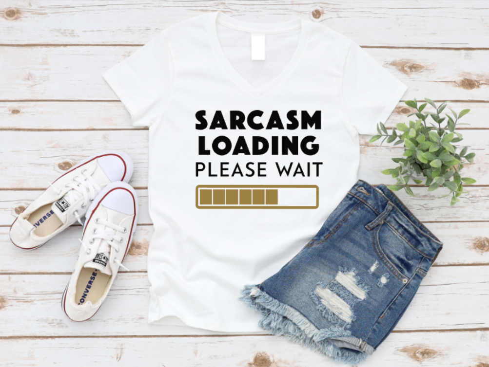 White t-shirt with 'Sarcasm Loading Please Wait' text, white sneakers, and denim shorts on a wooden surface. www.missmafia.com