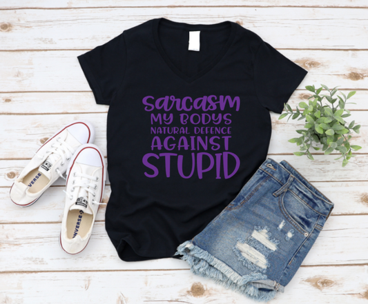 Black t-shirt with purple text on a wooden surface with shoes and shorts. www.missmafia.com