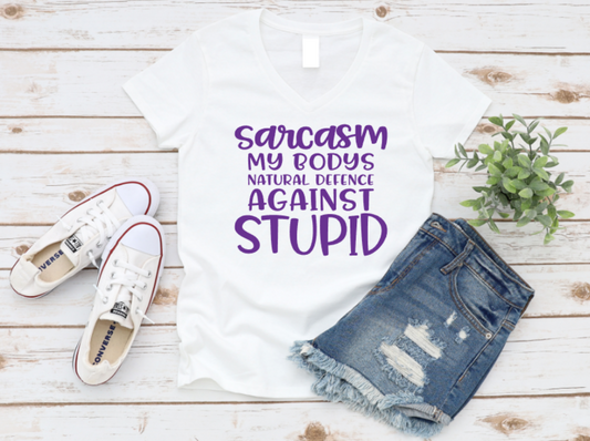 White t-shirt with purple text, blue jeans, and white sneakers on a wooden surface. www.missmafia.com