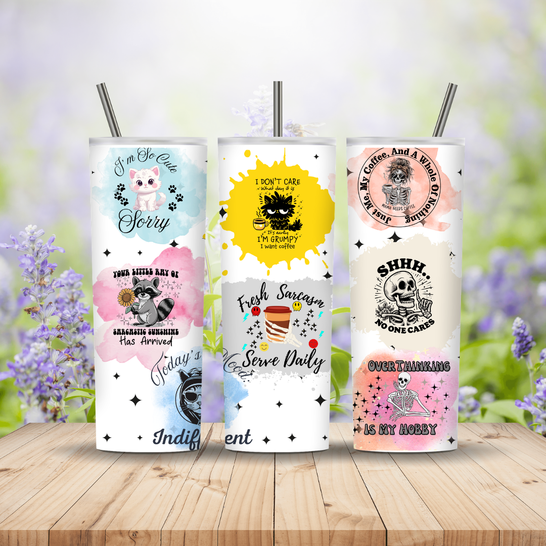 Three tumblers with different designs on a wooden surface with a blurred floral background