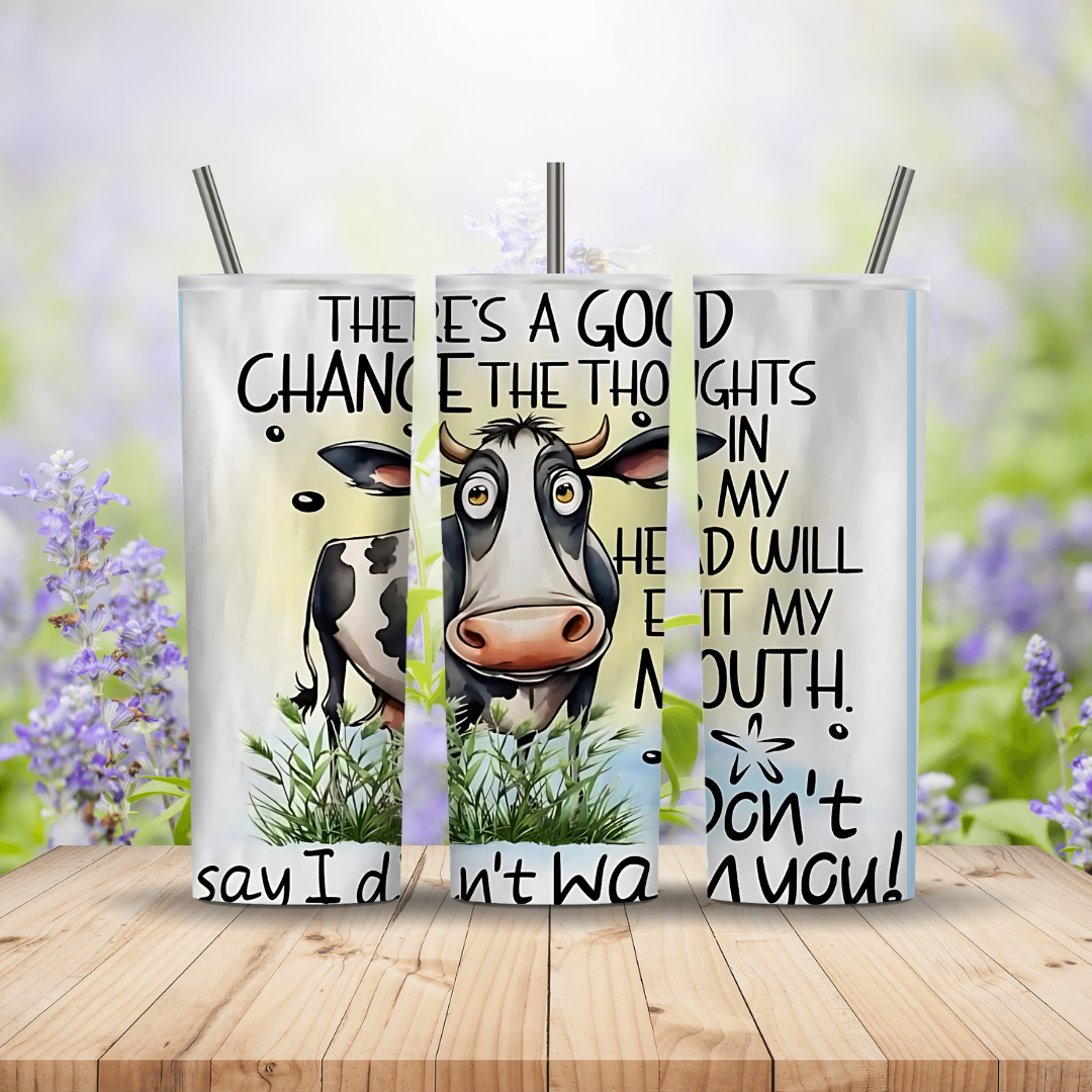 Two tumblers with a cow illustration and humorous text on a wooden surface with a blurred floral background.