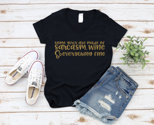 Black t-shirt with gold text on a wooden surface with shoes and shorts. www.missmafia.com