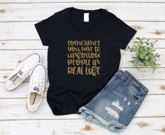 Black t-shirt with gold text, white sneakers, and denim shorts on a wooden surface. www.missmafia.com