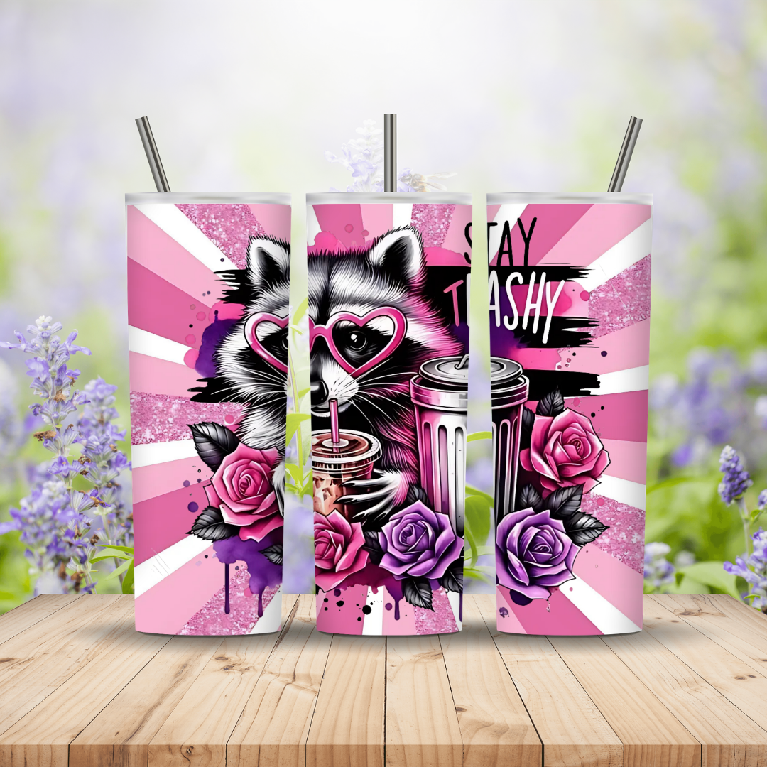 Three pink tumblers with a cat and floral design on a wooden surface with a blurred floral background.