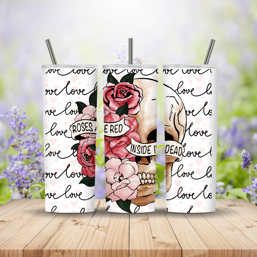 Three tumblers with floral and skull designs on a wooden surface with a blurred floral background.