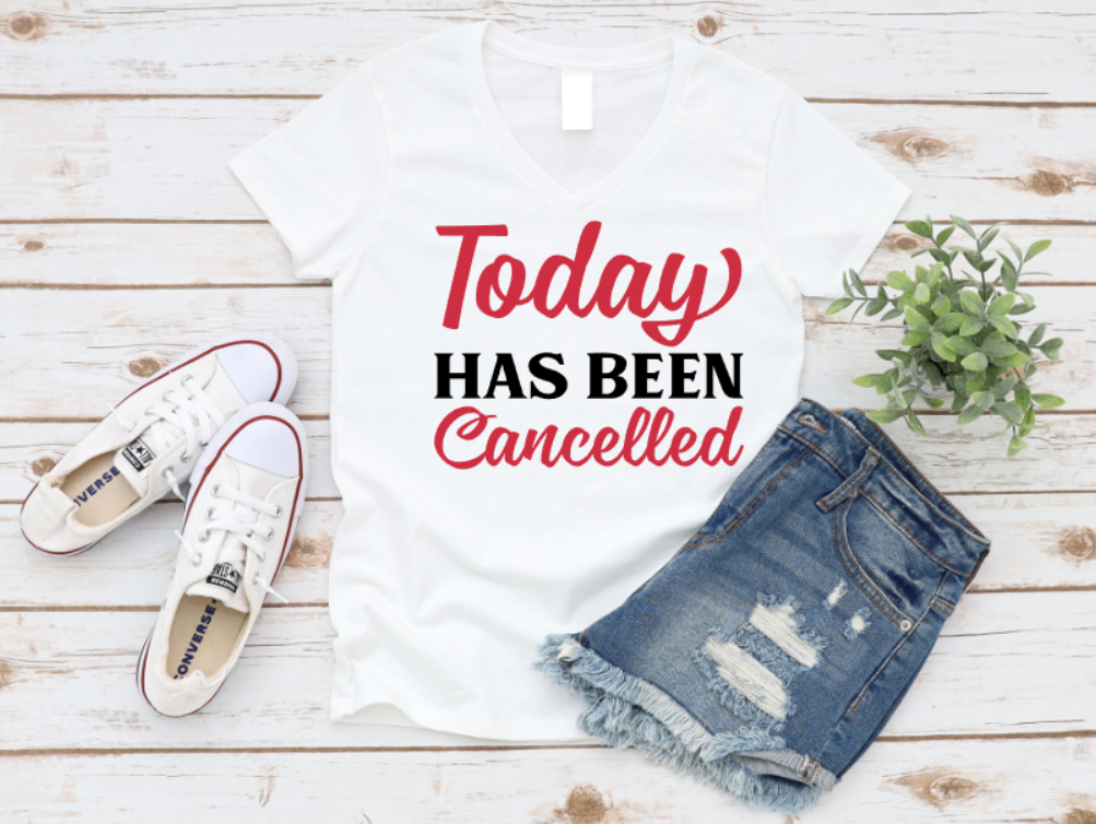 White t-shirt with 'Today Has Been Cancelled' text, white sneakers, and denim shorts on a wooden surface. www.missmafia.com