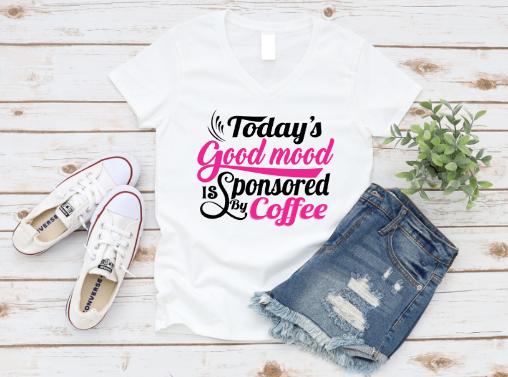 White t-shirt with 'Today's Good Mood is Sponsored by Coffee' text, paired with denim shorts and white sneakers on a wooden surface. www.missmafia.com