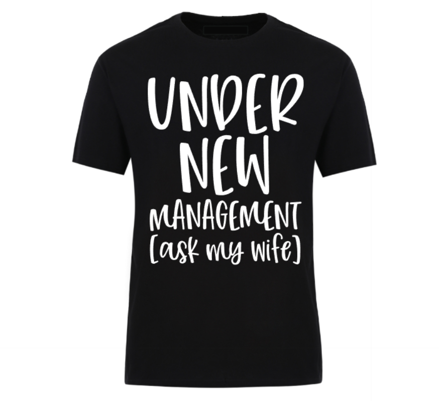 Black t-shirt with bold black text reading “Under New Management – See Wife for Details,” styled with casual denim and sneakers—funny gift for husbands or newlyweds.
