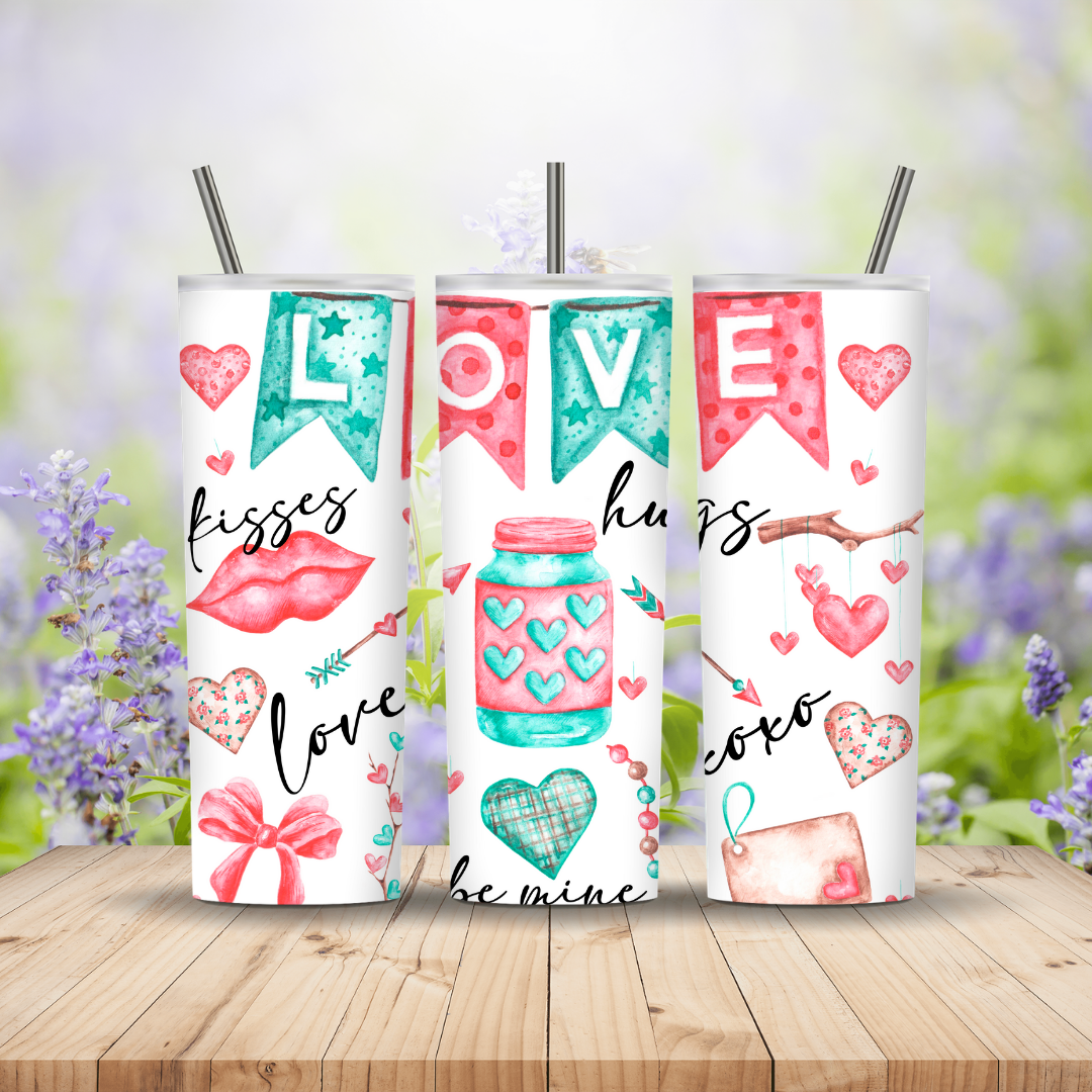 Three tumblers with love-themed designs on a wooden surface with a blurred floral background