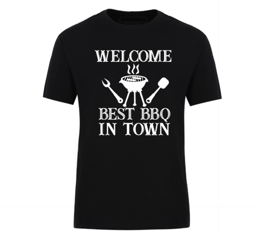 Black t-shirt with bold black text reading “Welcome Best BBQ in Town,” featuring grilling utensils and a barbecue grill graphic – perfect for BBQ dads, weekend warriors, and summer cookout kings.
