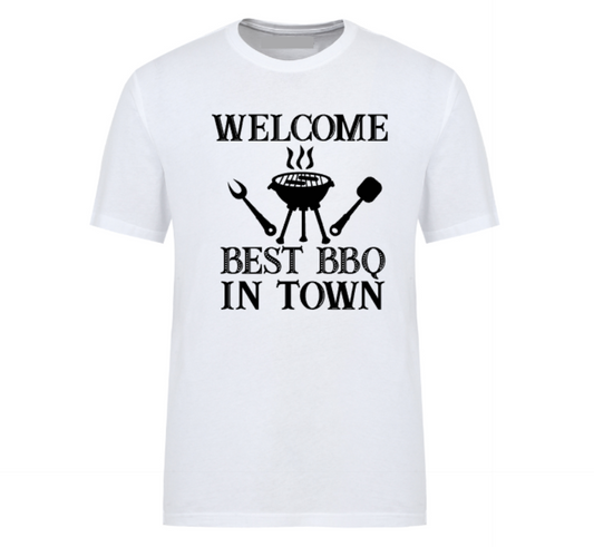 White t-shirt with bold black text reading “Welcome Best BBQ in Town,” featuring grilling utensils and a barbecue grill graphic – perfect for BBQ dads, weekend warriors, and summer cookout kings.
