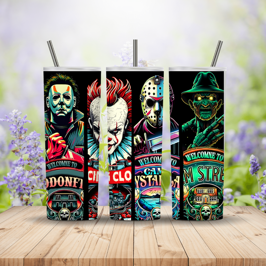 Five colorful horror-themed tumblers on a wooden surface with a blurred floral background