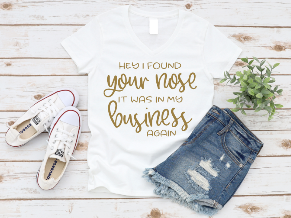 T-shirt with humorous text, denim shorts, and white sneakers on a wooden surface.