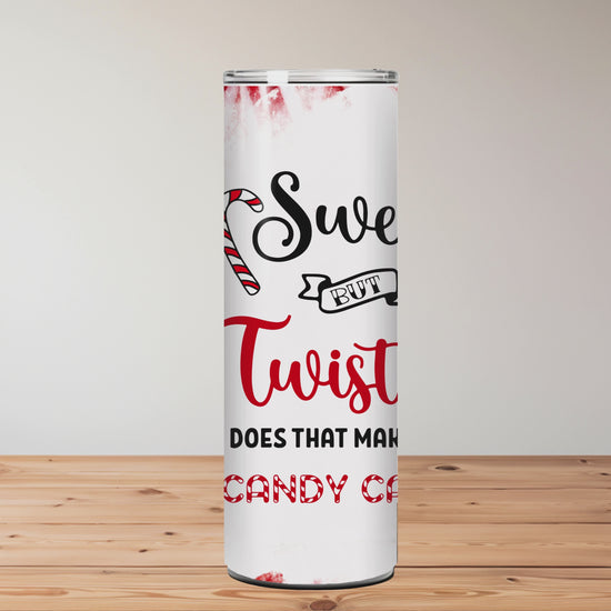 Tumbler with candy cane design and text on a wooden surface with blurred flowers in the background | Miss Mafia