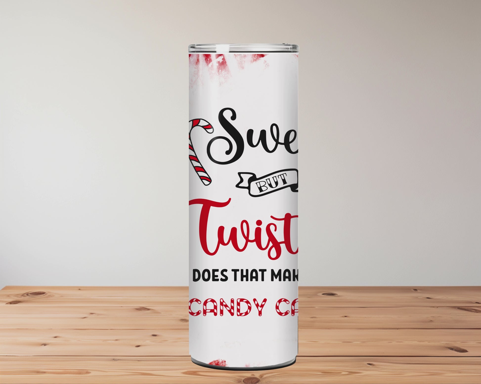 Tumbler with candy cane design and text on a wooden surface with blurred flowers in the background | Miss Mafia