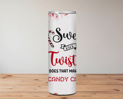 Tumbler with candy cane design and text on a wooden surface with blurred flowers in the background | Miss Mafia