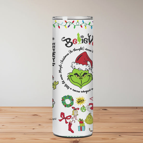 Christmas-themed tumblers with designs and text on a wooden surface with blurred floral background