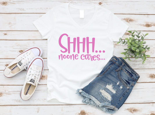 White t-shirt with 'SHHH... noone cares...' text, blue jeans, white sneakers on a wooden surface. www.missmafia.com