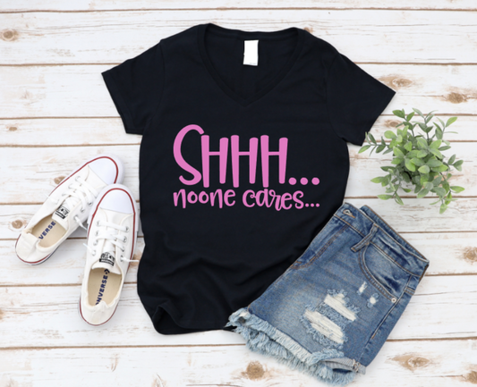 Black t-shirt with pink text 'SHHH... noone cares...' on a wooden surface with sneakers and shorts. www.missmafia.com