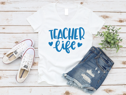 White t-shirt with 'Teacher Life' text, denim shorts, and white sneakers on a wooden surface. www.missmafia.com